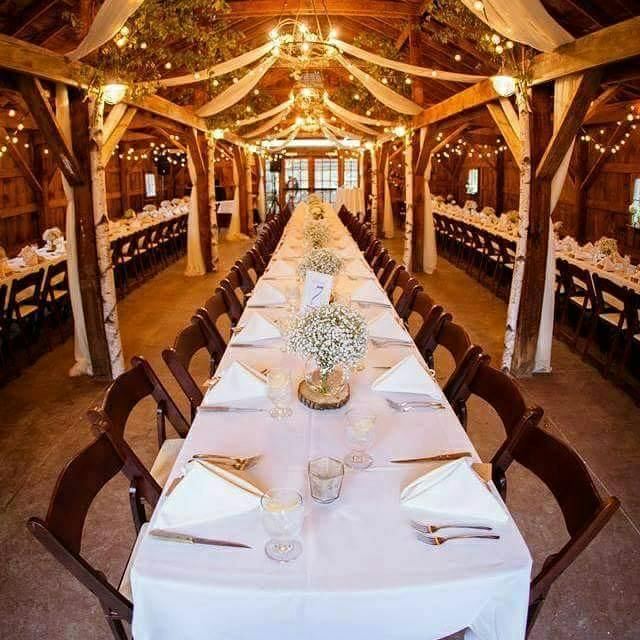 A long banquet table set for guests in a timber barn venue